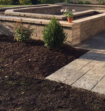 A residential masonry walkway accented with retaining walls, Shrubs and fresh mulch